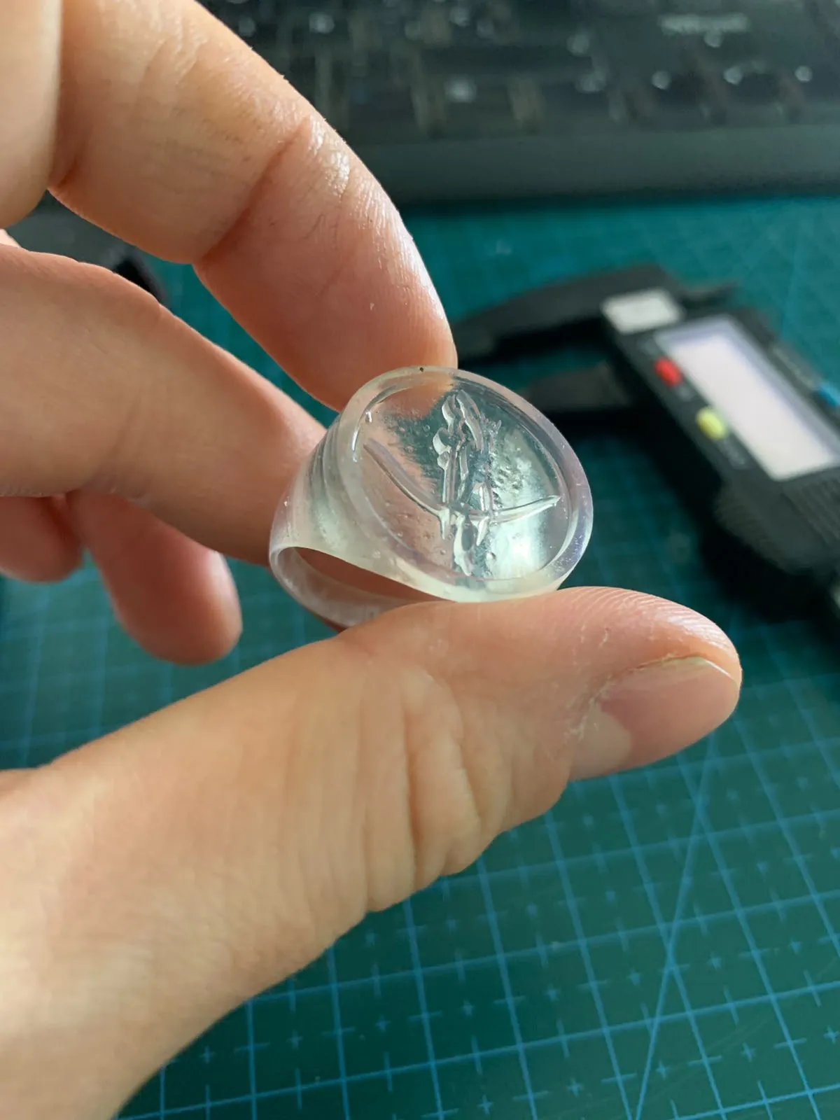 El anillo impreso en resina transparente, sostenido entre los dedos, con un calibre atrás