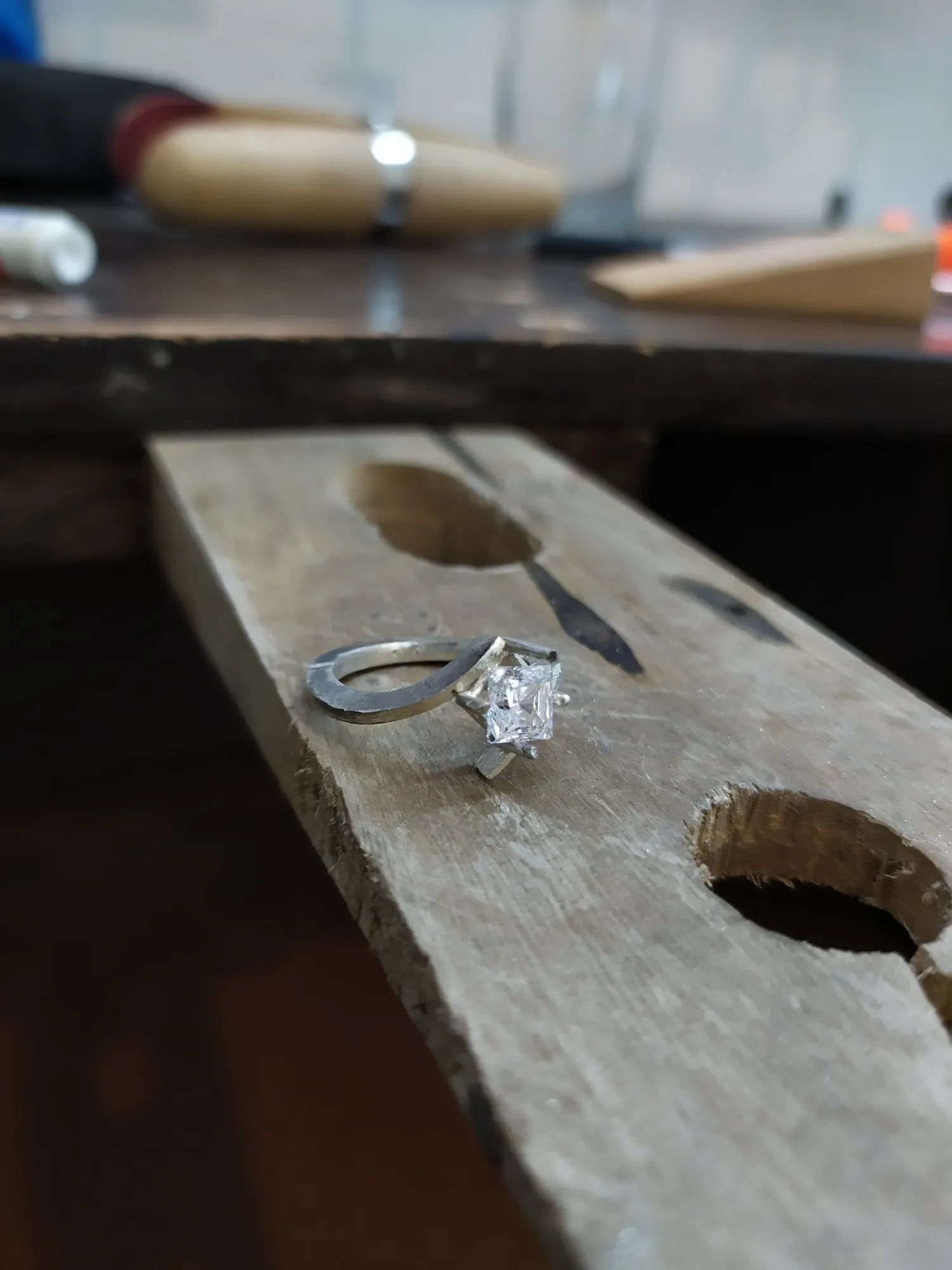 Anillo solitario con circonia cuadrada, apoyado en el taco del banco de joyero