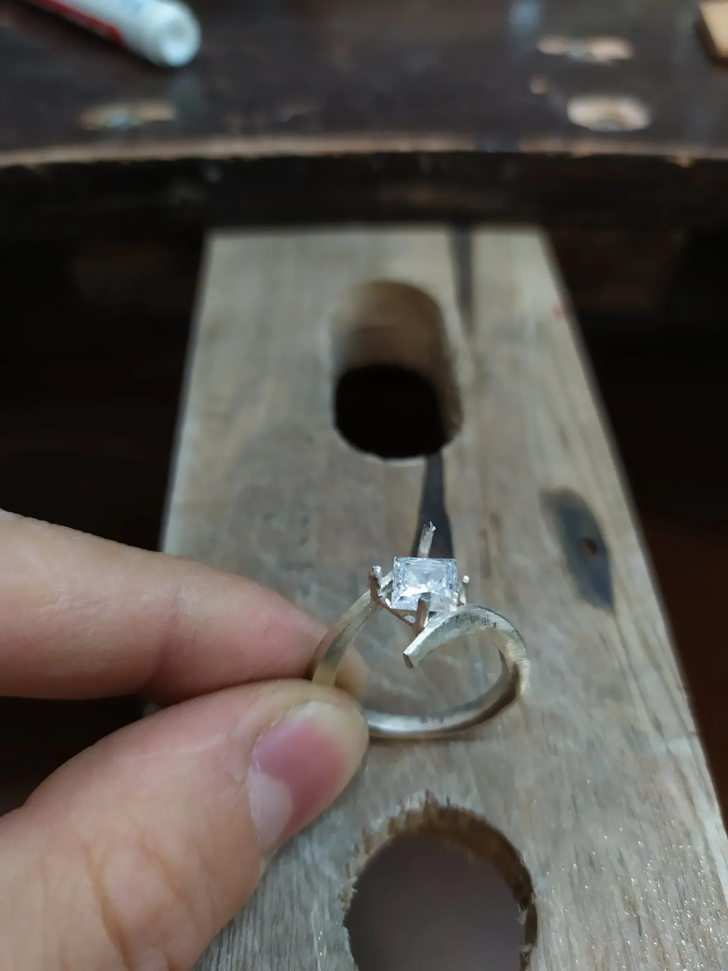 Anillo solitario con piedra blanca, sostenido en la mano