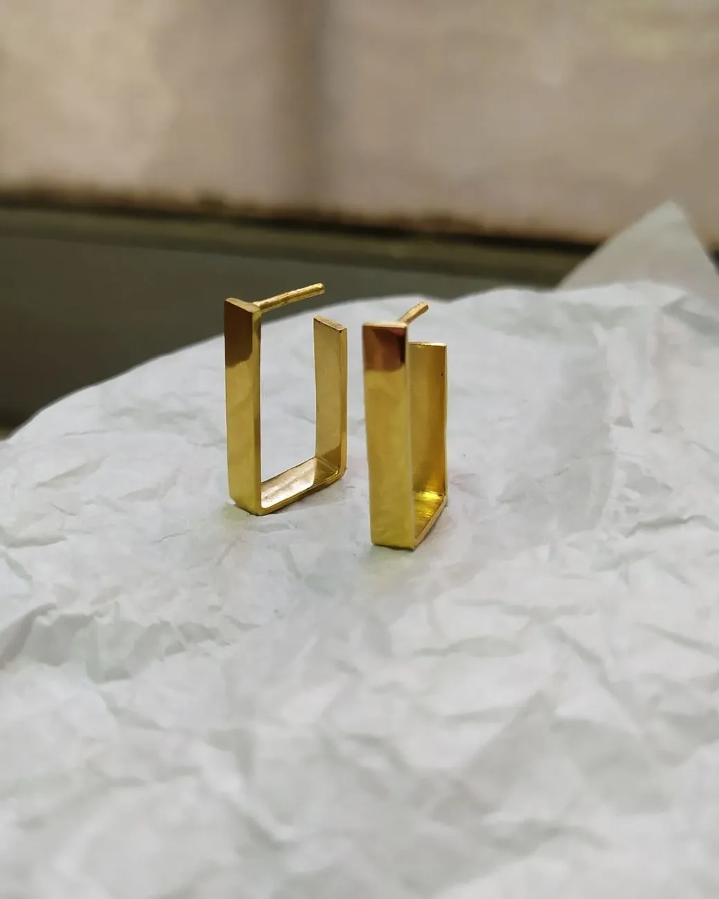 Par de aros rectangulares enchapados en oro, sobre papel de seda